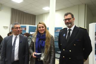 Deux hommes et 1 femme tenant une boîte avec une médaille