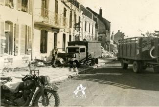 Les véhicules allemands circulent dans les rues de La Capelle encore marquées par les combats ©Arch. dép. Aisne 2 Fi 339