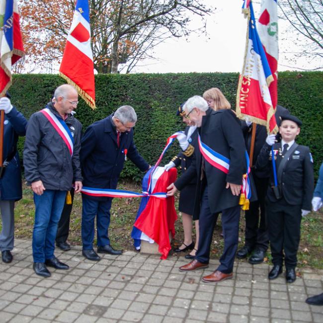 Porte-Drapeaux et personnalités officiels dévoilant une borne enveloppée d'un drapeau français (bleu blanc rouge)