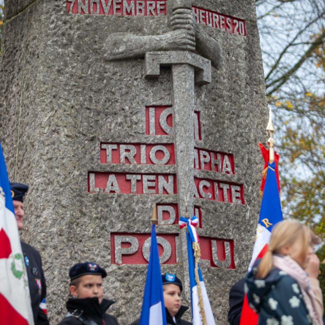 Jeunes porte-drapeaux devant un monument aux morts