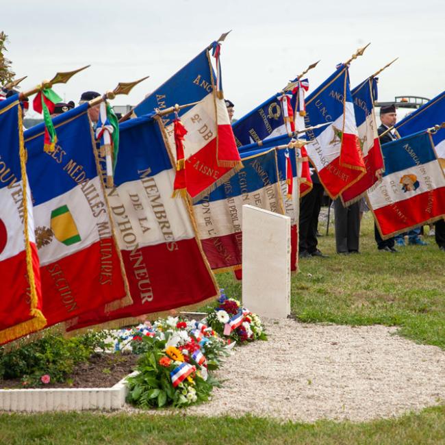 Alignement de porte-drapeaux lors de l’inauguration de la borne Aisne Terre de Mémoire à Flavy-le-Martel, avec gerbes déposées au pied du monument, le 31 mai 2026