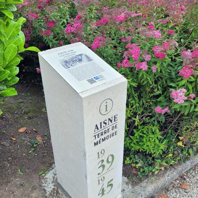 Borne Aisne Terre de Mémoire installée près d’un massif fleuri au monument du 23e Régiment de marche volontaire étranger (RMVE), inaugurée le 8 juin 2026